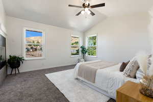 Primary bedroom featuring ceiling fan, vaulted ceiling, and ample natural light