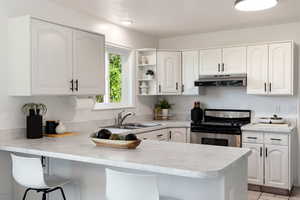 Kitchen with stainless steel range, peninsula, sink, and white cabinets