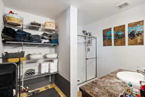 Bathroom featuring a shower with door and sink