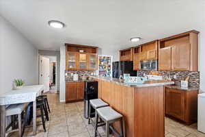 Kitchen featuring black fridge with ice dispenser, a kitchen island, a breakfast bar area, and tasteful backsplash