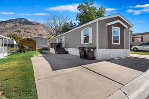 View of front of home with a storage shed, a mountain view, and a front yard