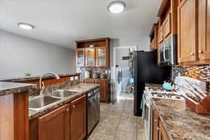 Kitchen with tasteful backsplash, light tile patterned floors, stainless steel appliances, washer / dryer, and sink