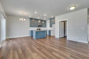 Kitchen featuring pendant lighting, stainless steel appliances, a center island, and wood-style floors