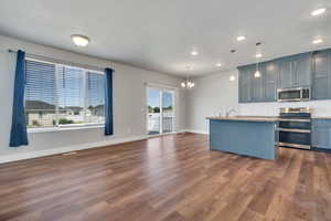 Kitchen with appliances with stainless steel finishes, hanging light fixtures, dark  wood-style floors, and gray cabinets