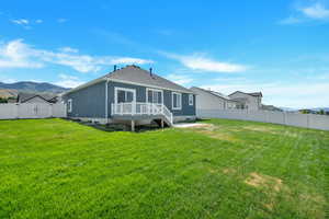 Back of property with a lawn and a deck with mountain view