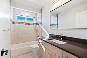 Full bathroom with tiled shower / bath, vanity, and toilet