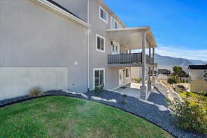 Rear view of house with a mountain view, a balcony, a yard, and a patio