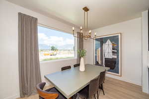 Dining space with a mountain view, light hardwood / wood-style floors, and a chandelier