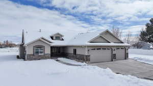 View of front facade with an attached garage, stone siding, and driveway