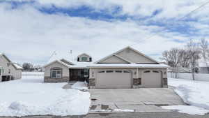 View of front of home featuring a garage, concrete driveway, and stone siding