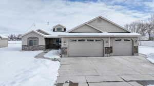 View of front facade featuring a garage, driveway, and stone siding