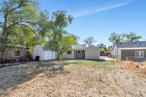 Rear view of house with a lawn and a shed