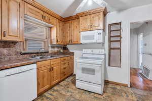 Kitchen with decorative backsplash, white appliances, and a sink