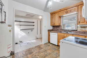 Kitchen featuring light brown cabinets, gas water heater, sink, and white appliances