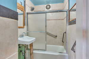 Bathroom featuring enclosed tub / shower combo and sink