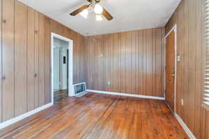 Living area with wood walls, ceiling fan, and hardwood / wood-style floors