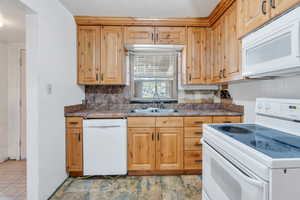 Kitchen with backsplash, sink, and white appliances