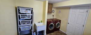 Laundry area featuring washing machine and clothes dryer, cabinets, and sink