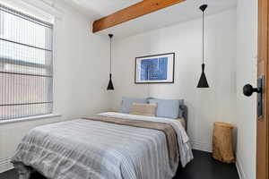 Bedroom with beam ceiling and dark hardwood / wood-style flooring