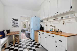 Kitchen featuring white cabinets, butcher block countertops, and sink