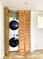 Laundry area with wood-type flooring, a textured ceiling, and stacked washer / dryer