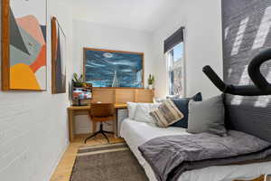 Bedroom featuring light wood-type flooring and brick wall