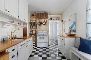 Kitchen with white cabinets, sink, and white electric range