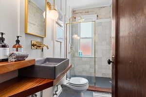 Bathroom with ornamental molding, vanity, toilet, and a shower with door