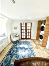 Living area featuring french doors, a textured ceiling, light wood-type flooring, and stacked washer / dryer