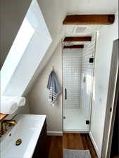 Bathroom with vanity, hardwood / wood-style flooring, lofted ceiling, and a shower with shower door