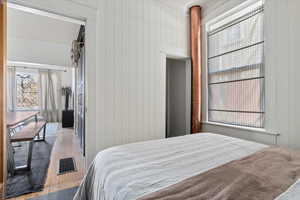 Bedroom with wooden walls and light wood-type flooring