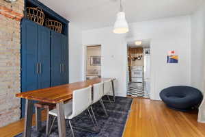 Dining space with brick wall and hardwood / wood-style floors