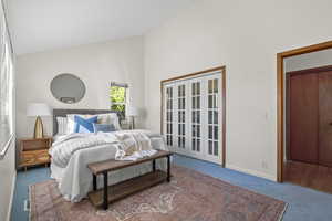 Bedroom featuring carpet floors, french doors, and high vaulted ceiling