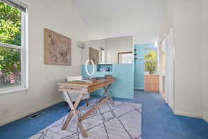 Home office with a wealth of natural light, lofted ceiling, and carpet flooring