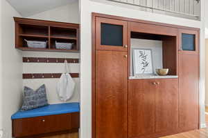 Mudroom with wood-type flooring and vaulted ceiling