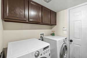 Clothes washing area featuring cabinets, a textured ceiling, and independent washer and dryer