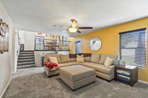 Carpeted living room with ceiling fan and plenty of natural light