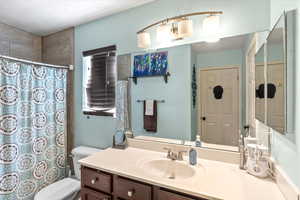 Bathroom featuring curtained shower, vanity, and toilet