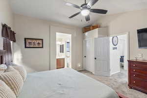 Bedroom featuring ensuite bath, light carpet, and ceiling fan