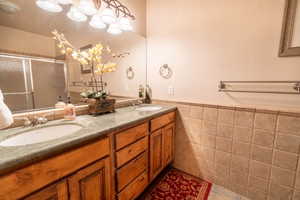 Bathroom featuring vanity, tile walls, a shower with shower door, and tile patterned flooring