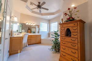 Bathroom with a bathtub, a raised ceiling, vanity, ceiling fan, and tile patterned floors