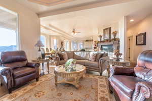 Living room featuring ceiling fan, light wood-type flooring, and a raised ceiling