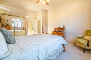 Bedroom with ceiling fan, a closet, and light carpet