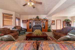 Carpeted living room featuring ceiling fan and a textured ceiling