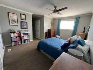 Bedroom featuring ceiling fan, a textured ceiling, crown molding, and carpet flooring