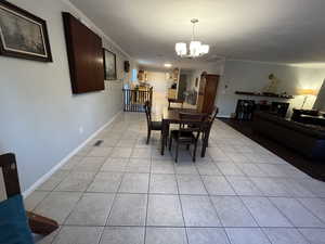 Tiled dining room with ornamental molding and an inviting chandelier