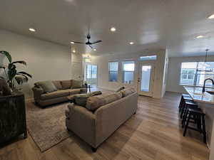 Living room with sink, light hardwood / wood-style flooring, a textured ceiling, and ceiling fan