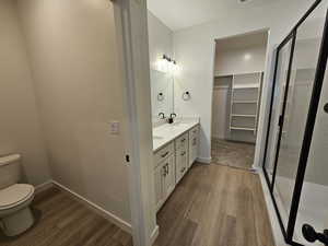 Bathroom with a shower with door, vanity, hardwood / wood-style floors, and toilet