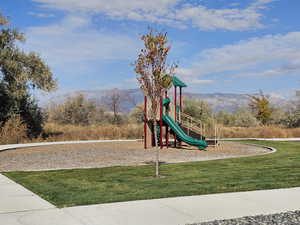 View of play area with a mountain view and a lawn