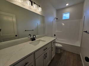 Full bathroom with toilet, hardwood / wood-style floors, vanity, and tub / shower combination